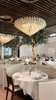 a dining room with tables and chairs, chandeliers hanging from the ceiling