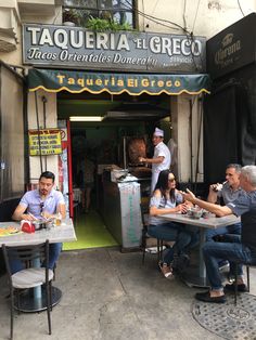 several people sitting at tables in front of a restaurant