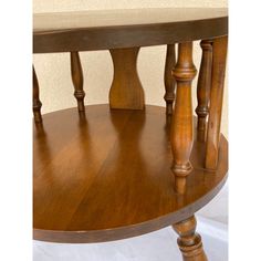 a round wooden table with three legs and a shelf on one side that has two drawers