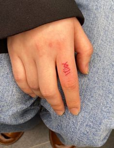 a person's hand with a small tattoo on their left thumb and the word love written in red ink