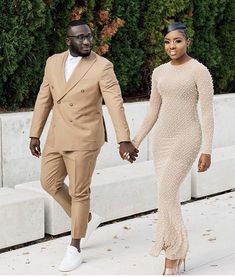 a man and woman in formal wear walking down the street holding hands with each other