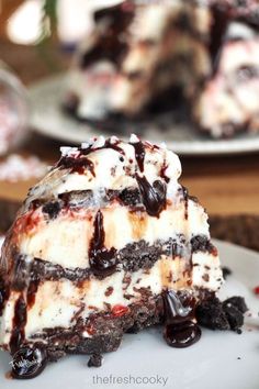 a piece of ice cream cake on a plate with chocolate sauce and oreo cookies