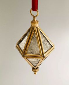 an ornament hanging from a red ribbon on a white wall in the shape of a diamond