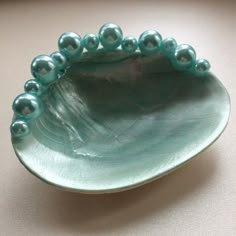 a green bowl with pearls in it on a table