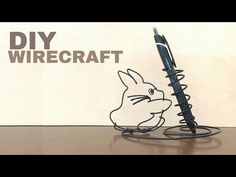 a pen sitting on top of a desk next to a wire holder with a rabbit drawn on it