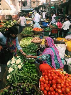 people shopping at an outdoor market with lots of vegetables