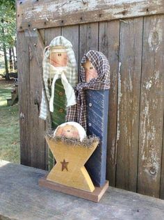 two wooden dolls sitting on top of a table next to a fenced in area