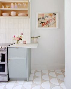 a kitchen with a stove, sink and cabinets in it's corner area that has white tiles on the floor