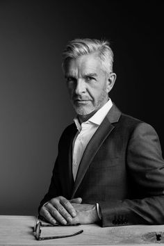 a man in a suit and tie sitting at a table with his hands on the desk