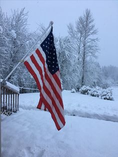 an american flag hanging from a pole in the snow