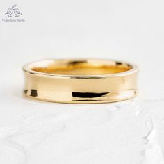 a yellow gold wedding ring on a white surface