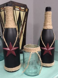 three wine bottles with twine wrapped around them on a table next to a stained glass jar