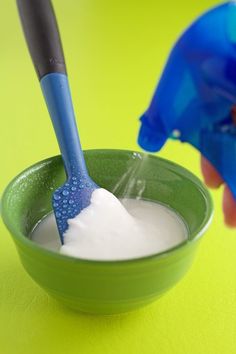 a blue toothbrush in a green bowl on a yellow table with white and blue liquid