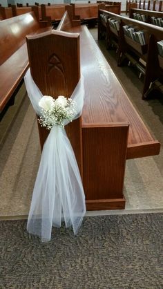 a wedding bouquet sitting on the back of a pew in a church with rows of pews