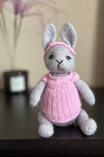 a small stuffed rabbit wearing a pink sweater