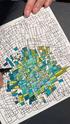 a person is holding a marker and drawing on a piece of paper with colored squares