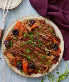 a white plate topped with meat and veggies on top of a wooden table