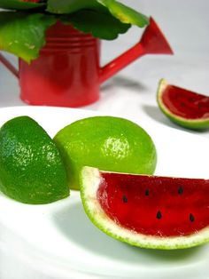 a white plate topped with slices of watermelon next to limes and a watering can