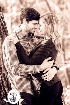 a man and woman embracing each other in front of a tree