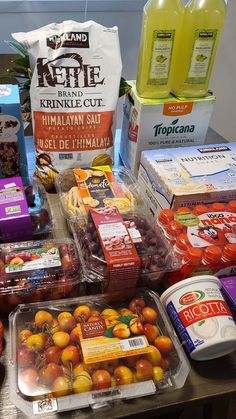 various fruits and vegetables on a table with juices, yogurt, eggs, and other items