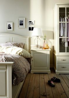 a bed room with a neatly made bed next to a night stand and dressers