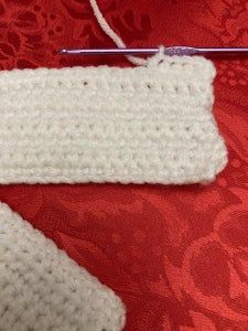 a crocheted pair of white gloves sitting on top of a red cloth