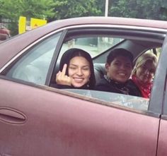 two people sitting in a car giving the peace sign