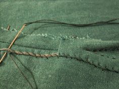 a pair of scissors is cutting through the fabric with some sewing thread on top of it