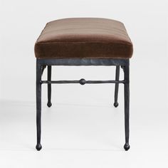 a bench with a brown cushion on it's seat and black metal legs, against a white background