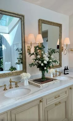 a bathroom with two sinks and mirrors on the wall next to it is decorated with flowers