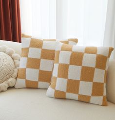 two brown and white pillows sitting on top of a couch