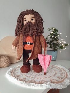 a crocheted doll holding an umbrella on top of a doily covered table