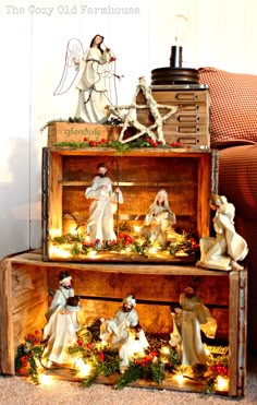 two wooden boxes filled with figurines sitting on top of each other in front of a christmas tree