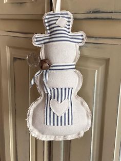 a white and blue snowman ornament hanging from the front door with a ribbon