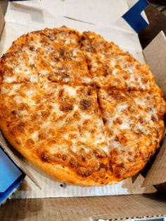 a pizza sitting on top of a cardboard box next to a blue box filled with cheese