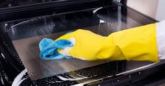 a yellow and blue cleaning glove sitting on top of an oven in the process of being cleaned