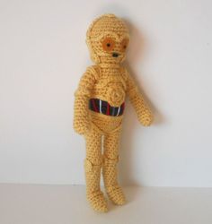 a crocheted teddy bear is posed against a white wall, wearing a star wars costume