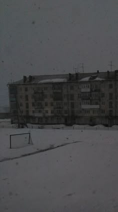 a snowboarder is going down a snowy hill in front of an apartment building