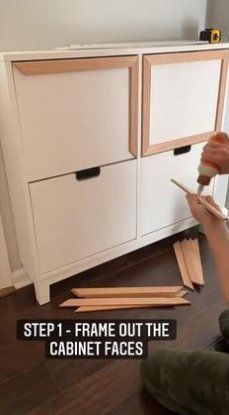 a person using a hammer to cut wood pieces on the floor in front of a cabinet