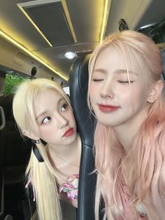 two young women sitting in the back of a car with their eyes closed and pink hair