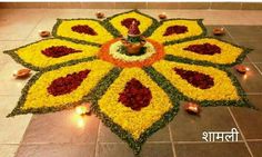 a decorated flower arrangement with candles on the ground in front of a tile floor that reads happy diwali