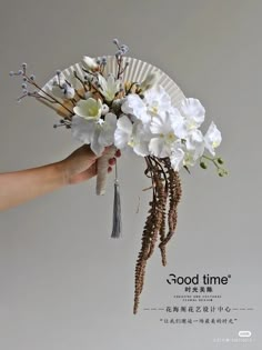 a hand holding a paper fan with flowers on it and the words good time written in chinese