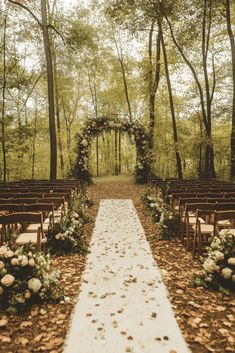 an outdoor ceremony setup with white flowers and greenery on the aisle, surrounded by trees