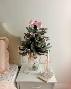 a small christmas tree sitting on top of a white table next to a pink bed