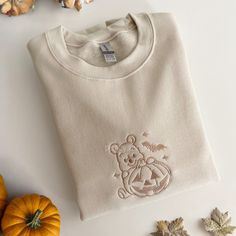 Stay warm this spooky season in our winnie the pooh pumpkin sweatshirt <3  SWEATSHIRT DETAILS: - 50% Cotton and 50% Polyester - Unisex sizing CARE INSTRUSCTIONS: - Machine wash cold - Do not iron on design, embroidered fabrics should always be ironed on the reverse side - Do not tumble dry NOTE: - Sweatshirts may slightly vary from each other or the image as each one is individually handmade - Each sweatshirt is made with care - All sales are final, if there are any issues do not feel afraid to contact me - No refunds *Winnie The Pooh is now on the public domain - copyright free* Machine Embroidered Sweatshirt Ideas, Cute Sweatshirts For Women, Winnie The Pooh Sweater, Winnie The Pooh Sweatshirt, Fall Sweatshirt Ideas, Embroidered Sweatshirt Ideas, Fall Disney Outfits, Winnie The Pooh Pumpkin, Bear Halloween