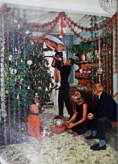 a group of people decorating a christmas tree in a living room with ornaments on the walls