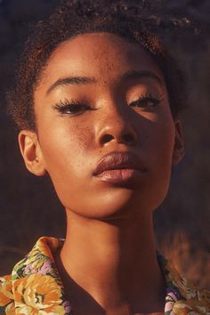 a young woman with her eyes closed wearing a floral shirt and looking off to the side