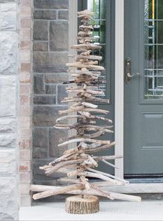 a tree made out of driftwood sitting in front of a door