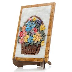 a basket filled with flowers sitting on top of a white tile wall next to a wooden frame