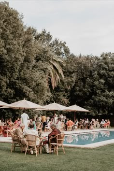 people are sitting at tables by the pool